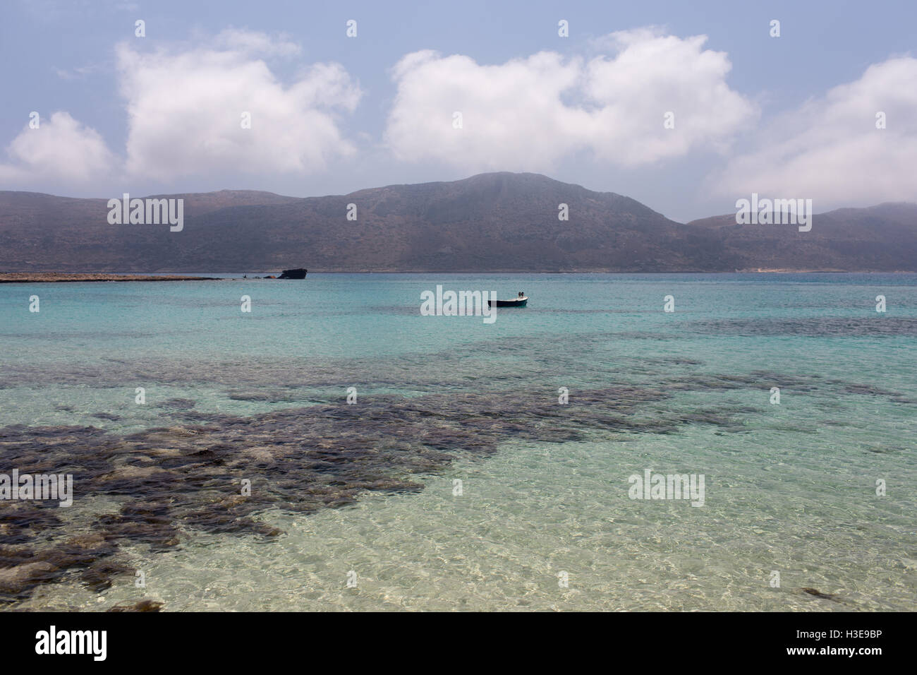A small fishing boat in a quiet bay on the background of mountains and ...
