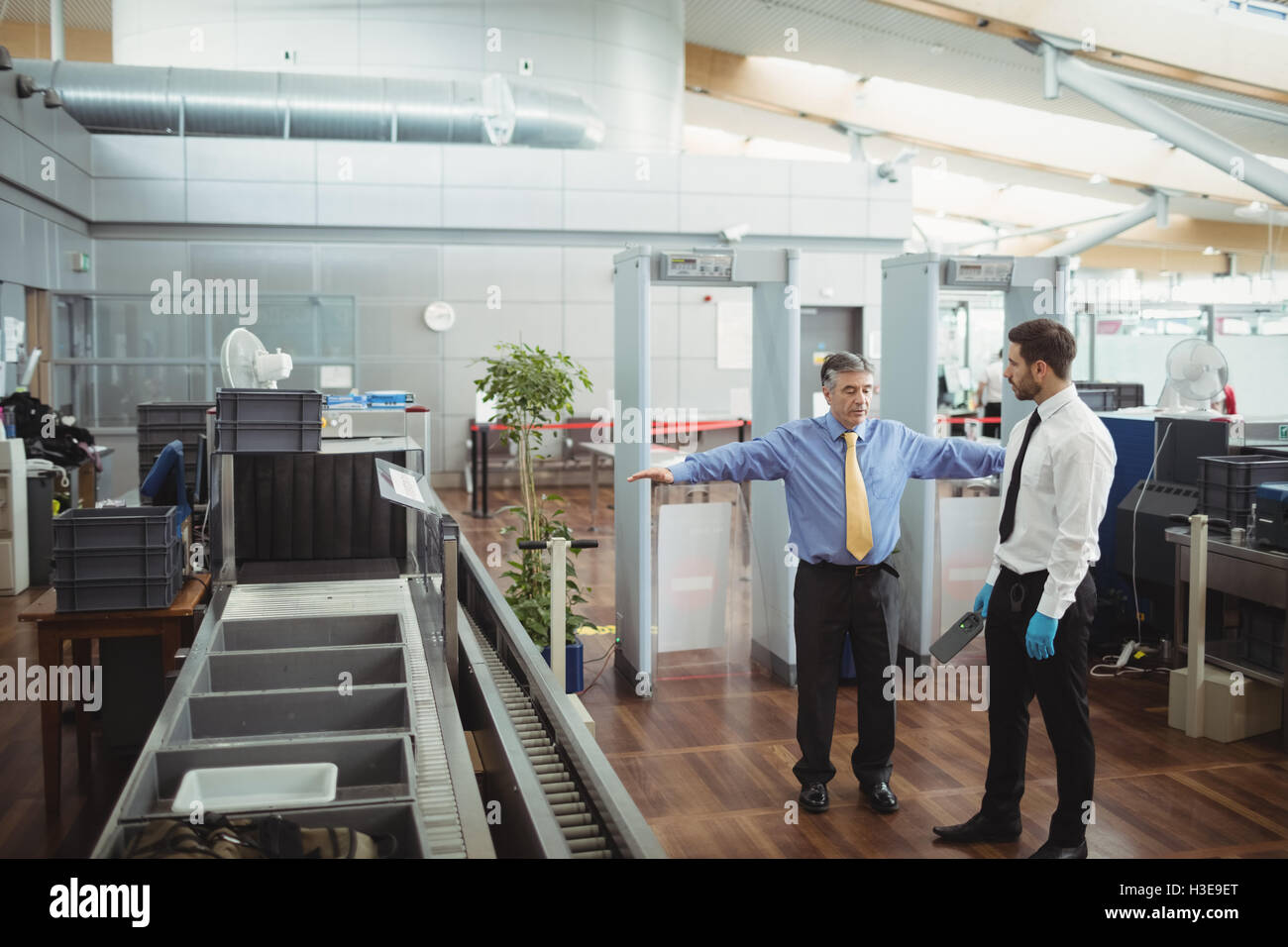 Airport security officer using a hand held metal detector to check a
