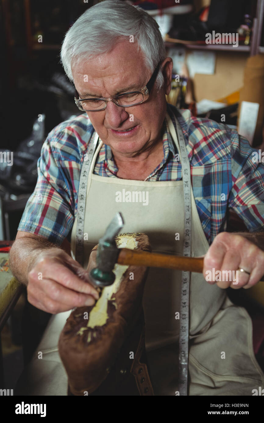 Shoemaker hammering on a shoe Stock Photo