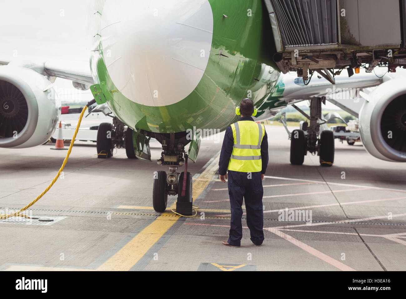 Rear view of airport ground crew worker directing airplane Stock Photo