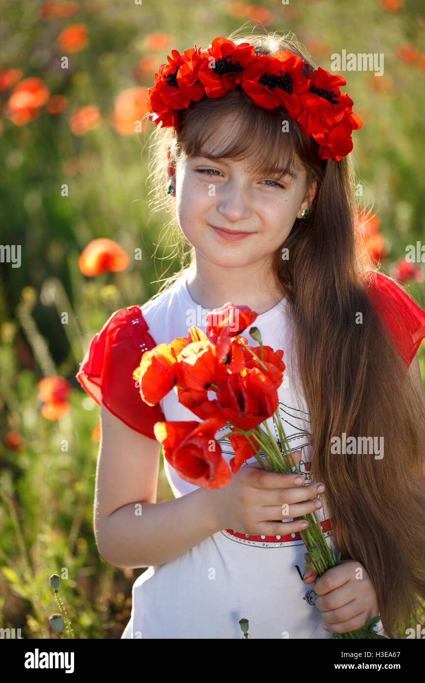 Portrait of a cute little girl in the meadow with poppies Stock Photo