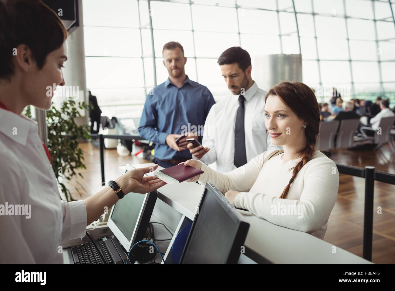 Woman giving her passport to airline check-in attendant Stock Photo