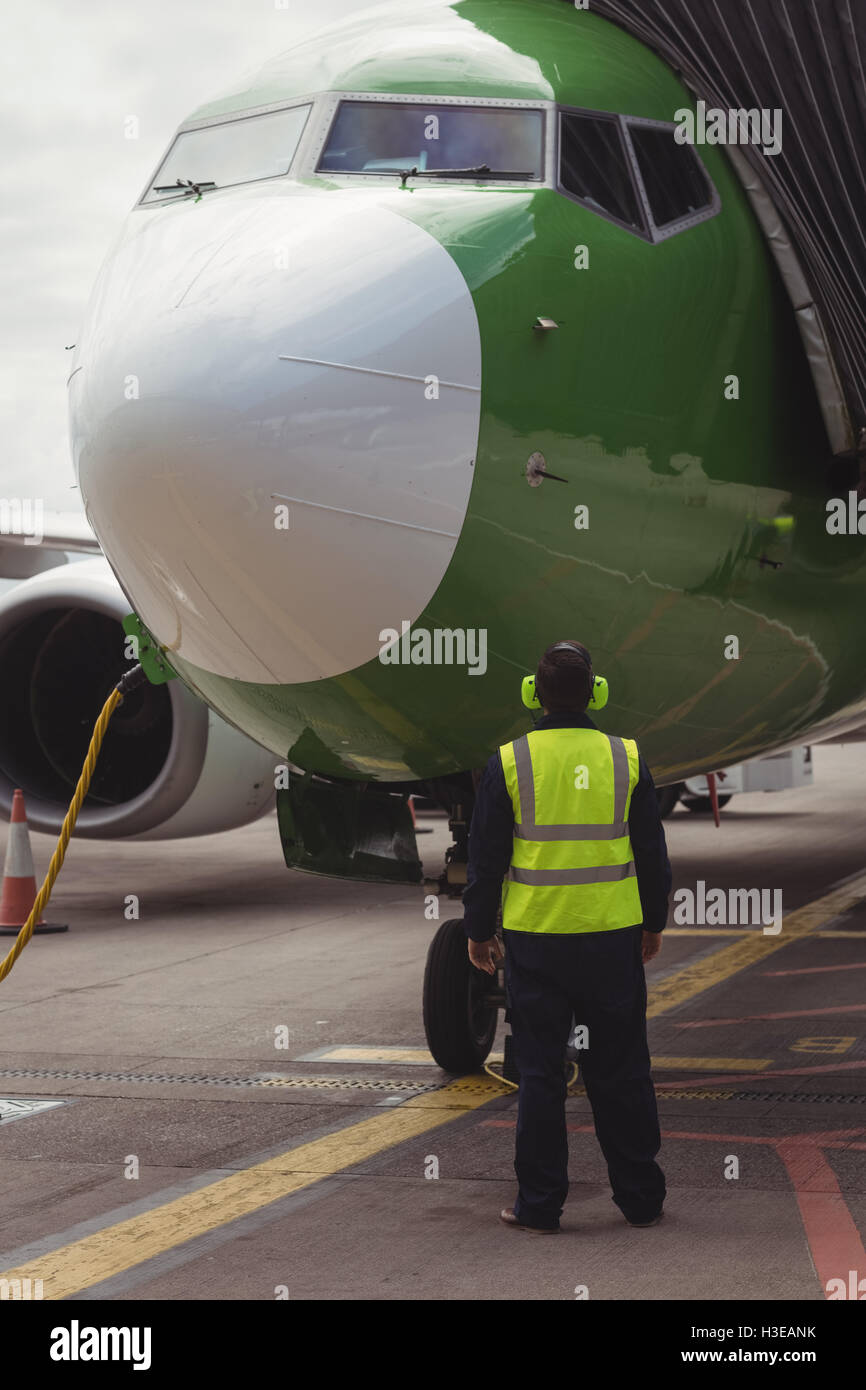 Rear view of airport ground crew worker directing airplane Stock Photo