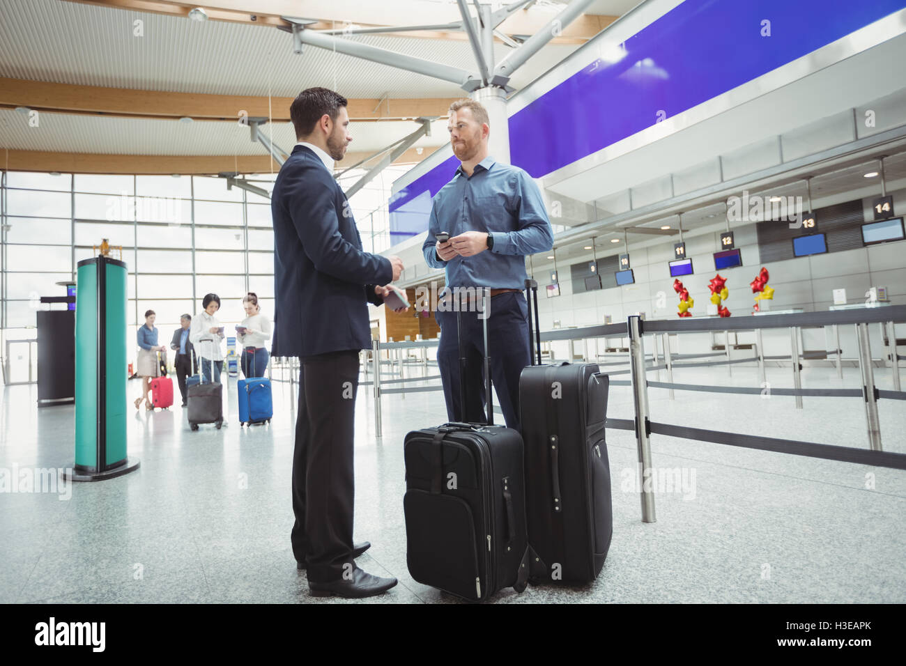 Business people waiting at check-in counter with luggage Stock Photo