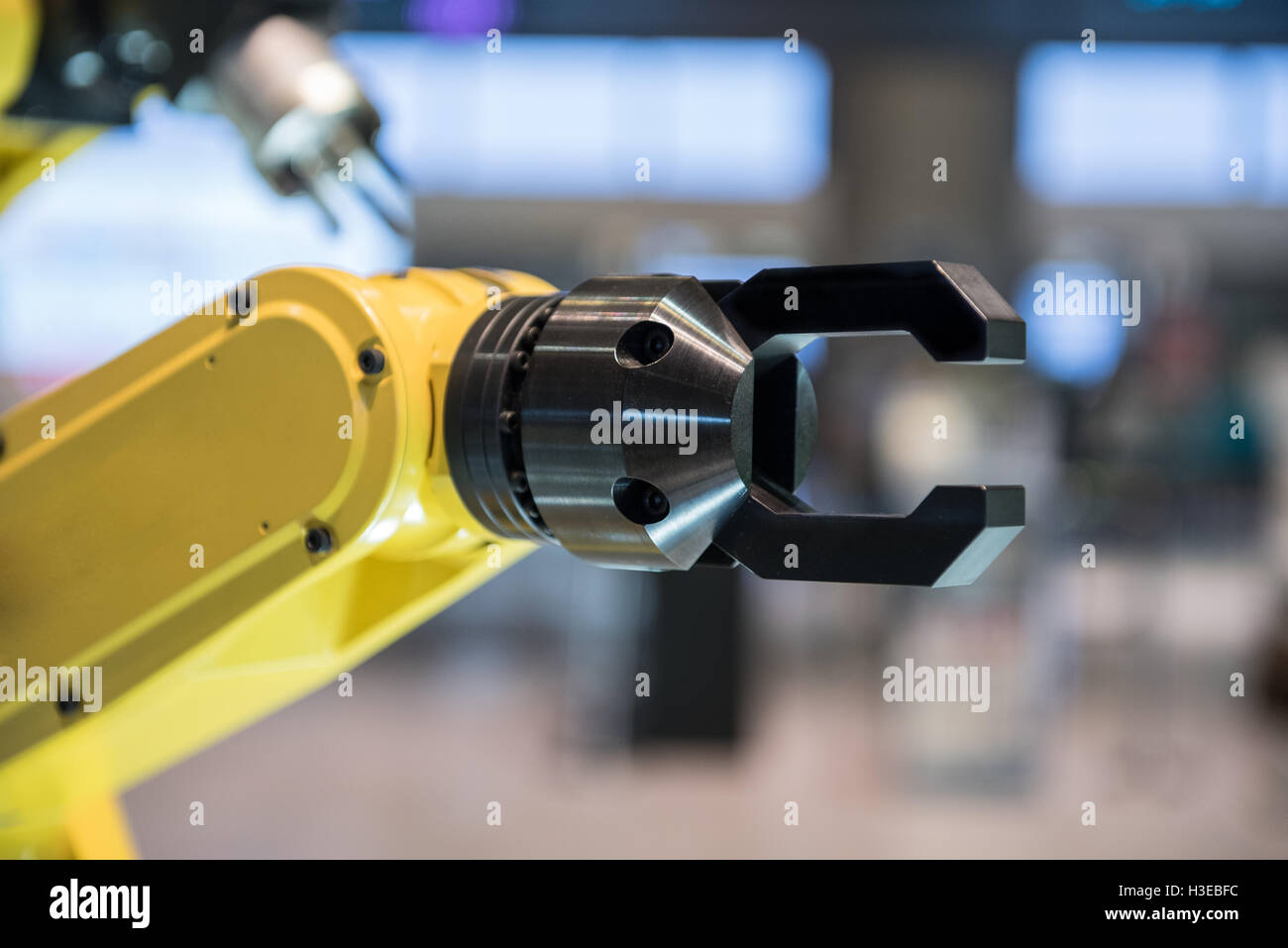 A yellow robotic arm isolated on a blurry background Stock Photo