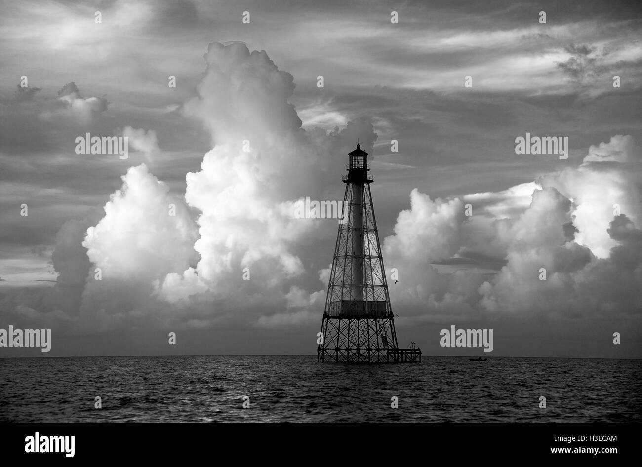 Once the site of a shipwreck, Alligator Reef Light looks beautiful at dawn with summer clouds side-lit by the rising sun. Stock Photo