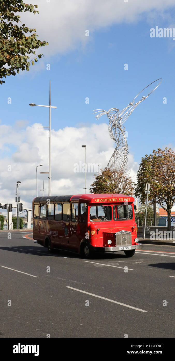 Red single-decker city tourist sightseeing bus on Oxford Street, Belfast, Northern Ireland with the Beacon of Hope sculpture in the background. Stock Photo