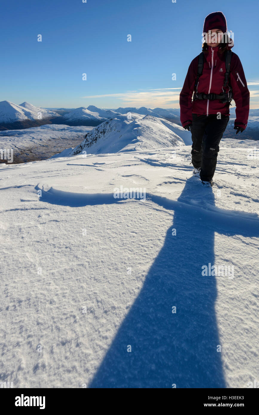 Female hill walker ascending the Munro Ben Challum in winter conditions, near Crianlarich