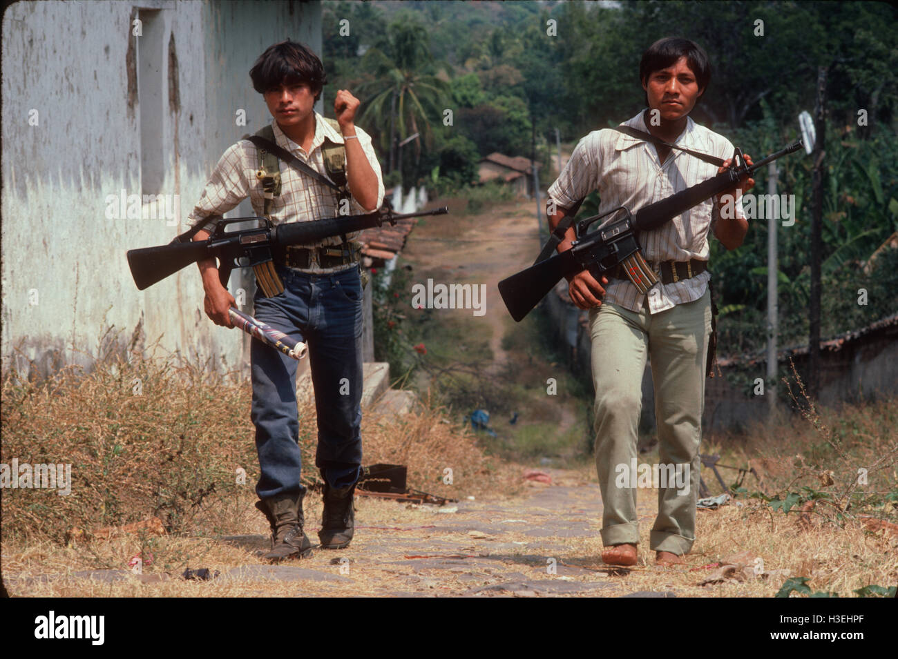 TENANCINGO,  EL SALVADOR, MARCH 1984: - Within the FPL Guerrilla's Zones of Control.  Two guerrilla fighters make their way through the abandoned streets of this contested town. Stock Photo