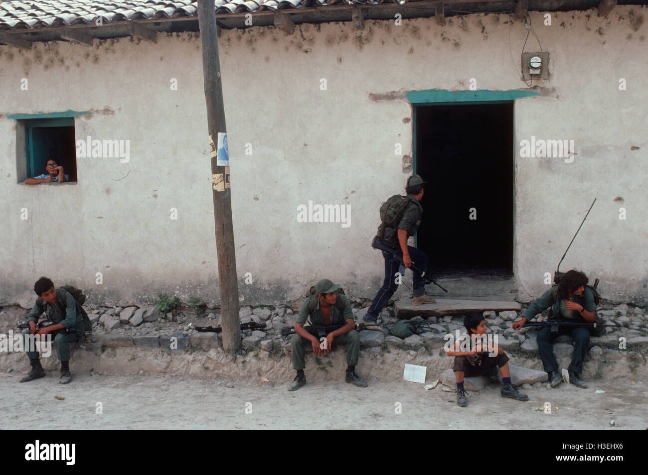 TENANCINGO,  EL SALVADOR, MARCH 1984: - Within the FPL Guerrilla's Zones of Control.  Guerrilla fighter outside a shop that still functions in the partly ruined town of Tenancingo. Stock Photo