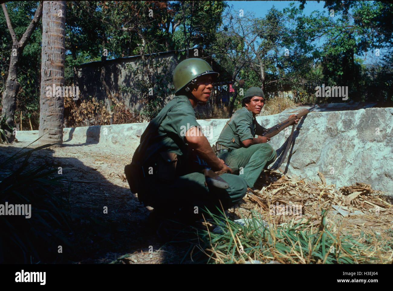 CUSCATANCINGO, SAN SALVADOR, EL SALVADOR, MARCH 1982: Salvadoran army soldiers take a battle with guerrillas at the entrance to a  graveyard. Stock Photo