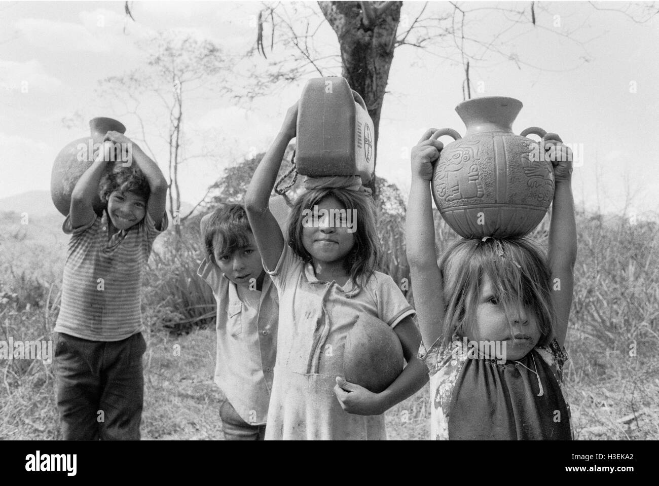 CHALATENANGO,  EL SALVADOR, FEB 1984: - Within the FPL Guerrilla's Zones of Control   Children carry water home from a stream. Stock Photo
