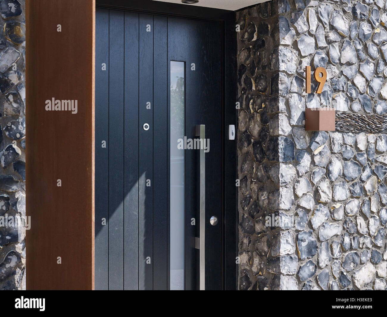 Entrance to the house. Black door with flint and rusted corten steel. House 19, Old Amersham, United Kingdom. Architect: Jestico + Whiles, 2016. Stock Photo
