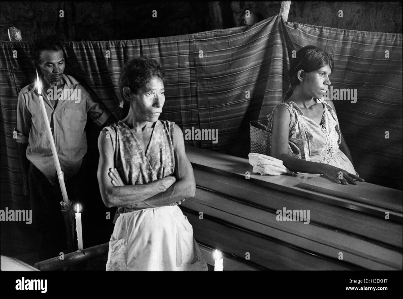 EL TRIUMFO, EL SALVADOR March 1982: Wives wait with the coffins of their husbands, militia members at El Triumfo killed the day before in battle with guerillas, before the funeral procession moved off. Stock Photo