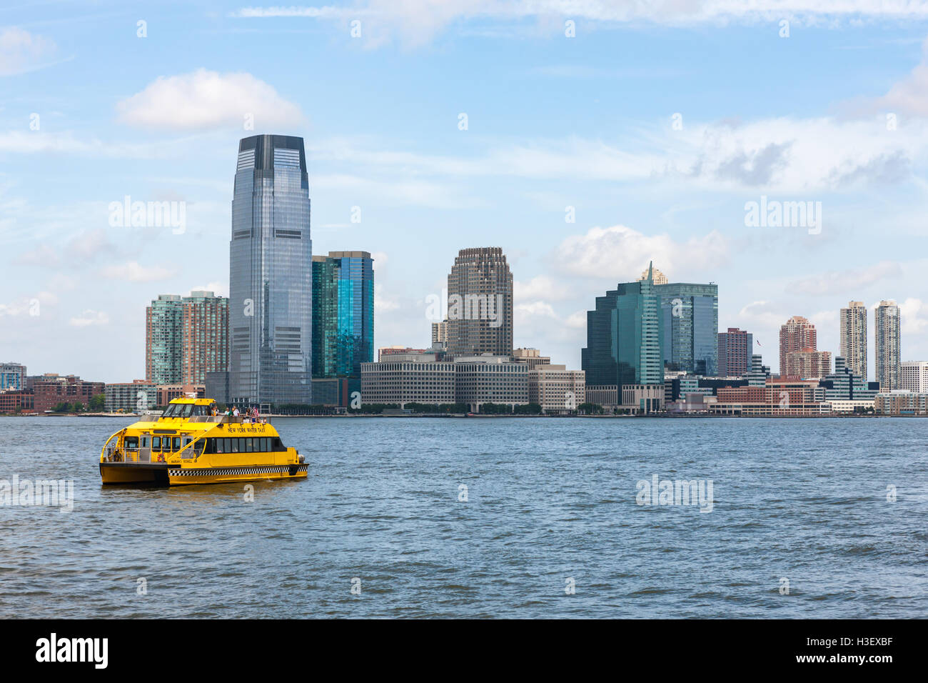 A New York Water Taxi heads south on the Hudson River past the Goldman Sachs Tower and skyline of Jersey City, New Jersey. Stock Photo