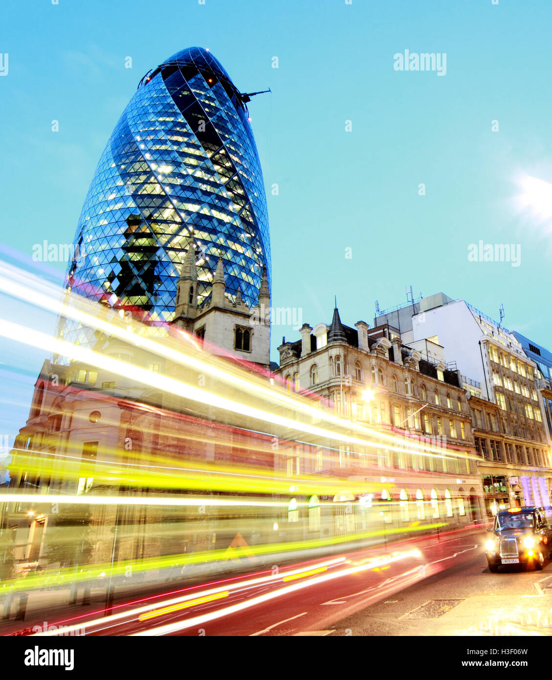 Red London bus passes 30 St Mary Axe,Gherkin,Swiss Re Building,City Of London,England at Dusk Stock Photo