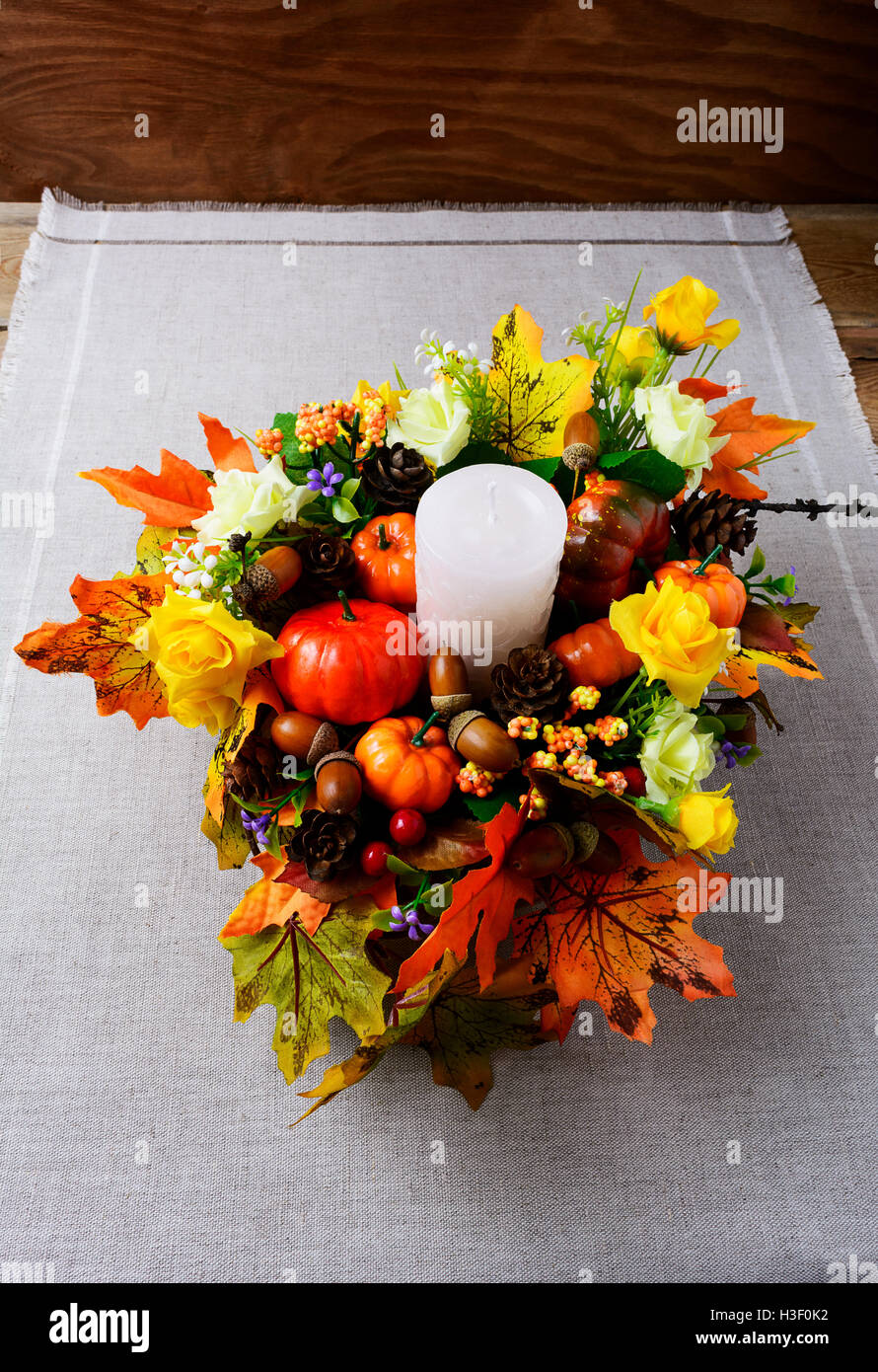 Fall decoration with candle and silk maple leaves, vertical. Thanksgiving greeting with fall decor. Fall centerpiece. Thanksgivi Stock Photo