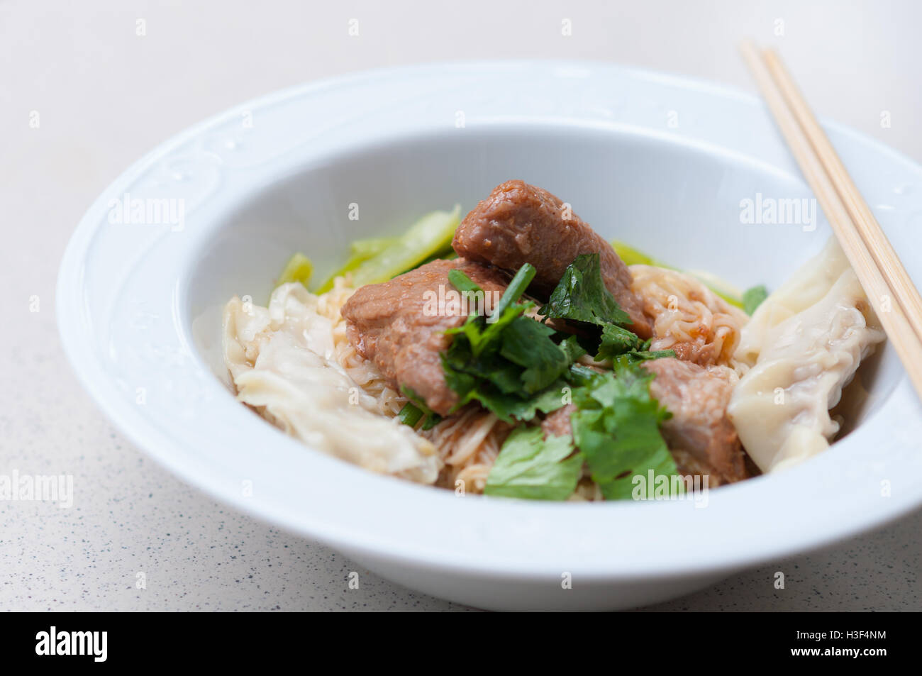Egg noodle with delicious stewed pork and dumpling in white bowl. Stock Photo