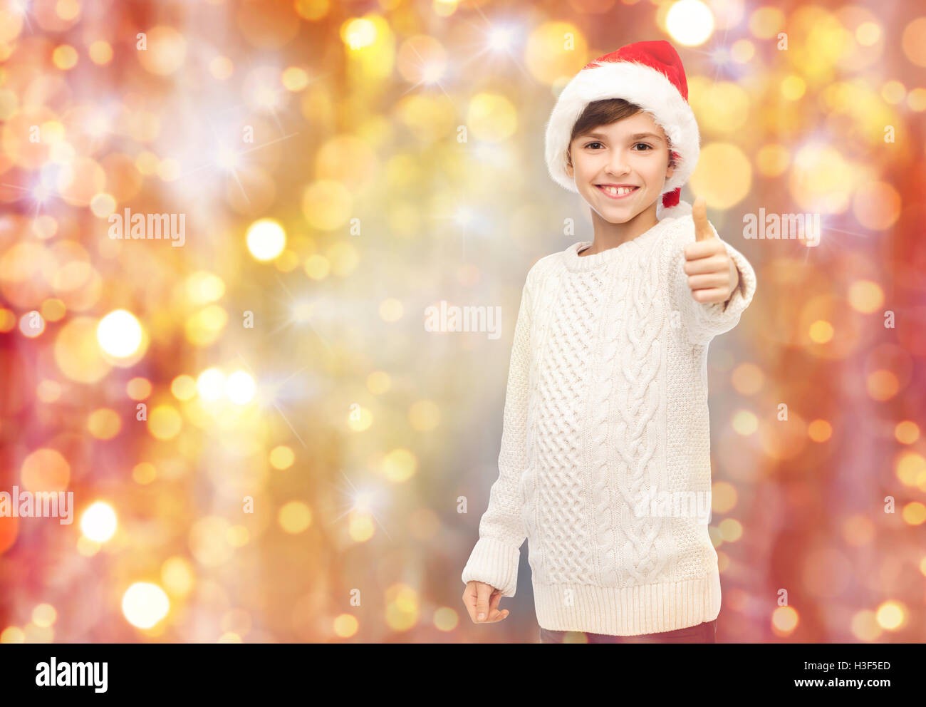 smiling happy boy in santa hat showing thumbs up Stock Photo