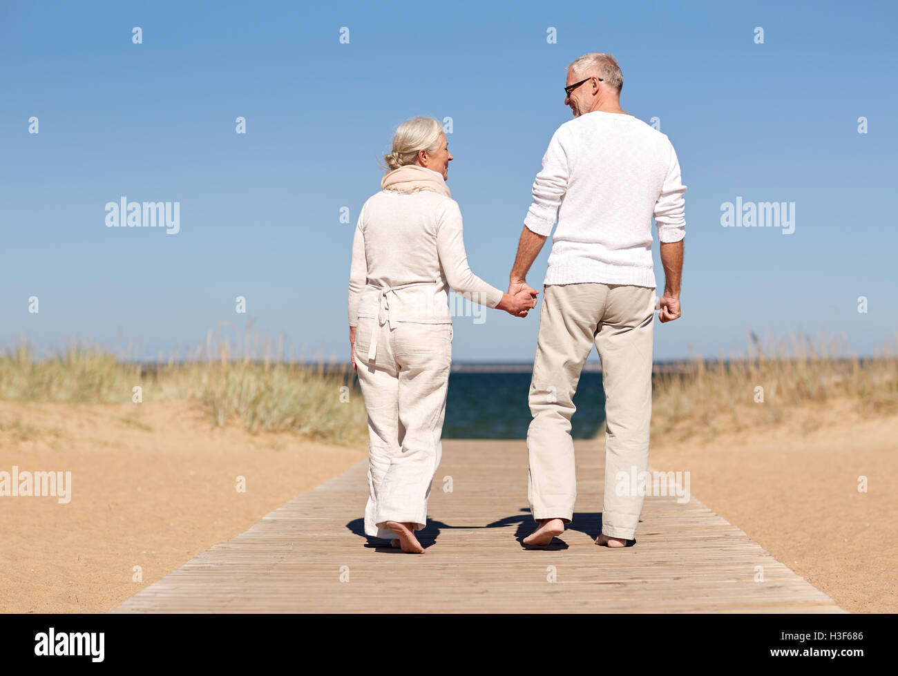 happy senior couple holding hands on summer beach Stock Photo - Alamy
