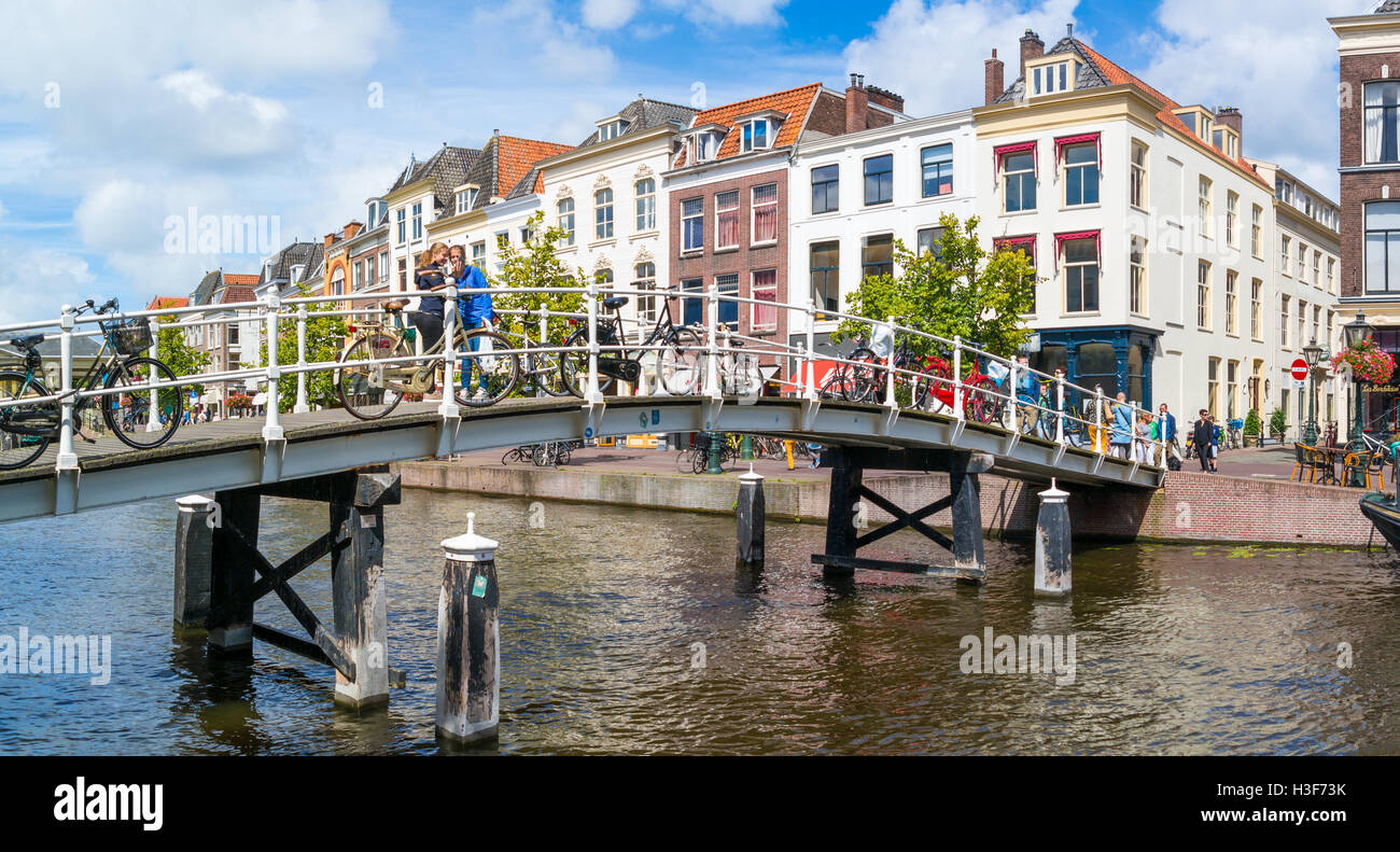 People and bicycles on bridge over New Rhine canal and gables of historic houses in downtown Leiden, South Holland, Netherlands Stock Photo