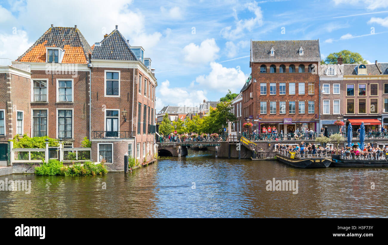 People at outdoor cafes, bridge and historic gables on quay of Old Rhine canal in downtown of Leiden, South Holland, Netherlands Stock Photo