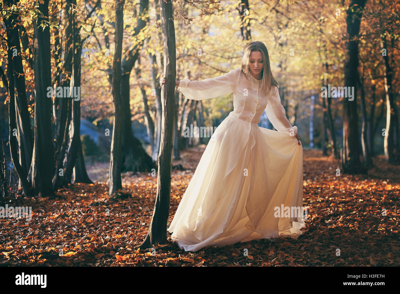 Woman with victorian dress dancing in autumn woods. Seasonal colors Stock Photo