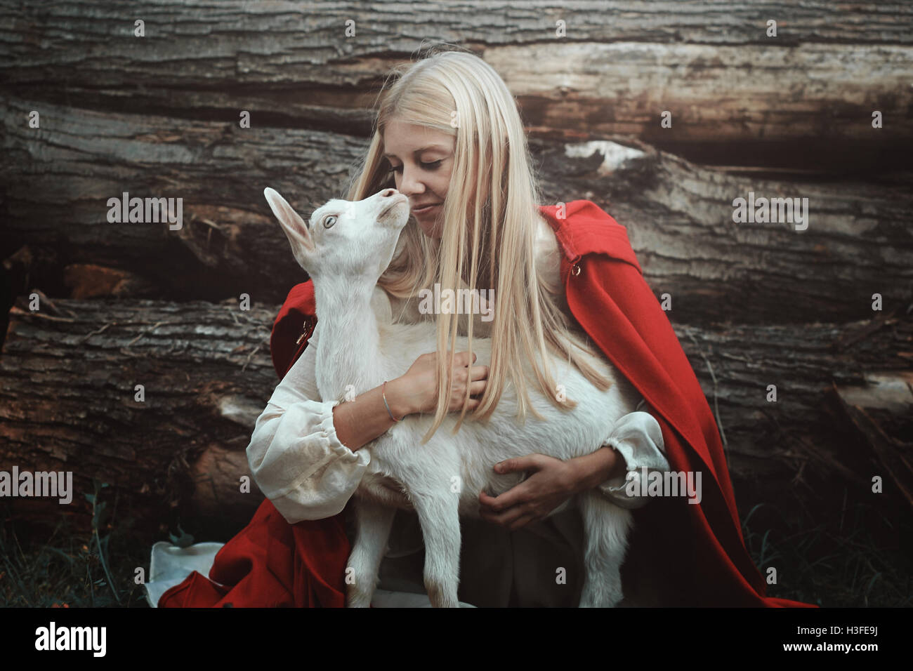 Funny portrait of blond woman and her goat. Friendship and love Stock Photo