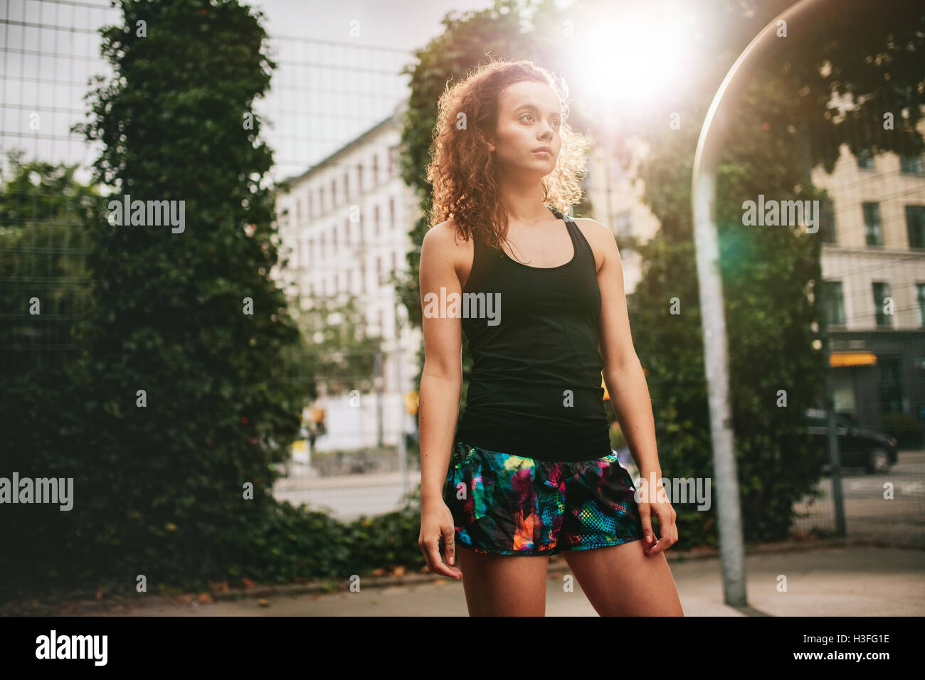 Portrait of attractive young girl standing on basketball court. Hipster in casuals looking away. Stock Photo