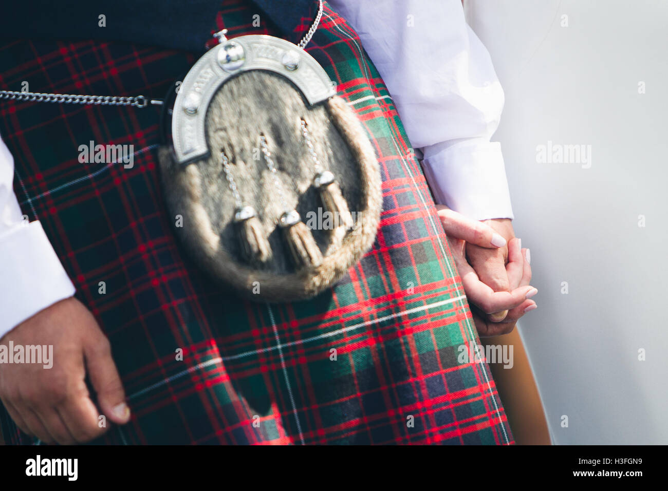 groom wearing kilt holding hands with bride Stock Photo