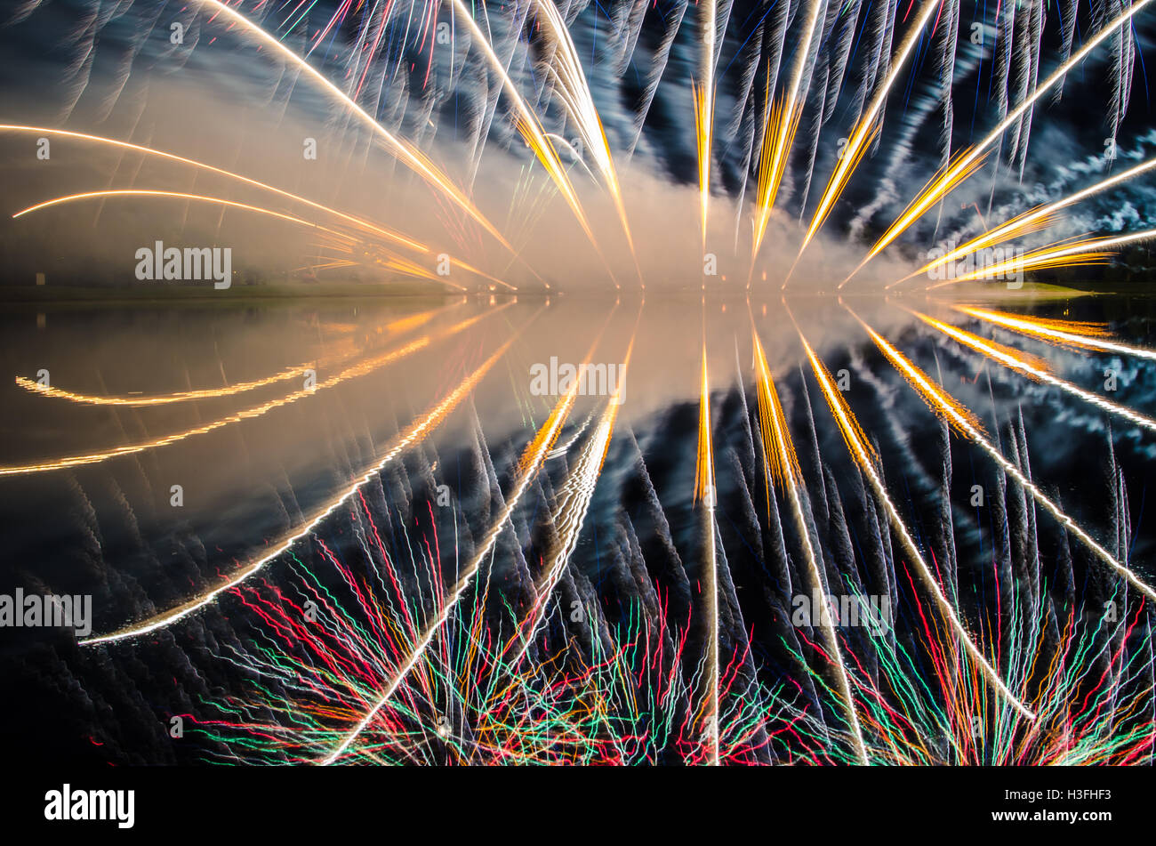 Fireworks streaky lines reflecting on water at night Stock Photo