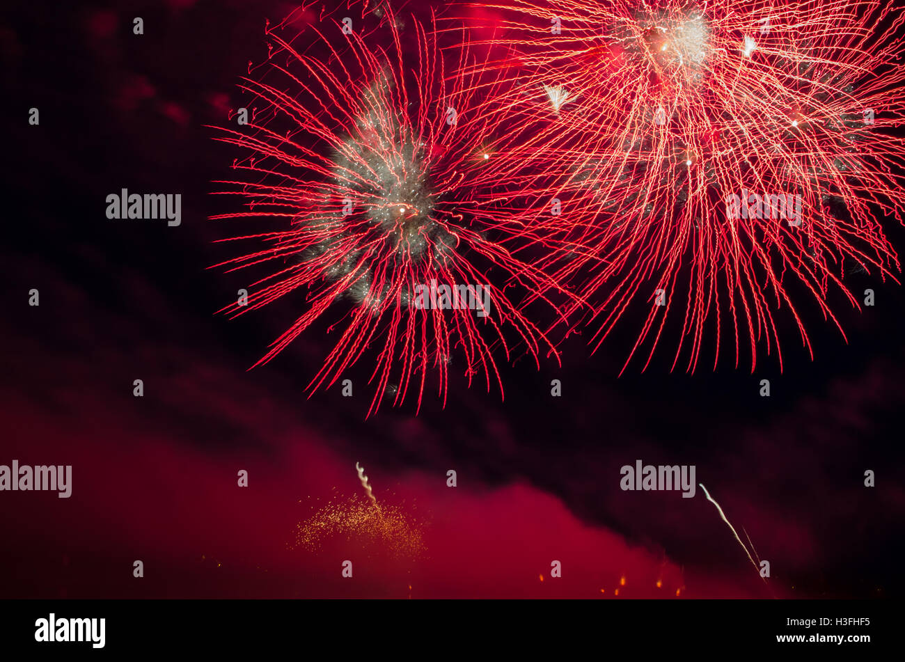 Red bursts and smoke from fireworks at night Stock Photo