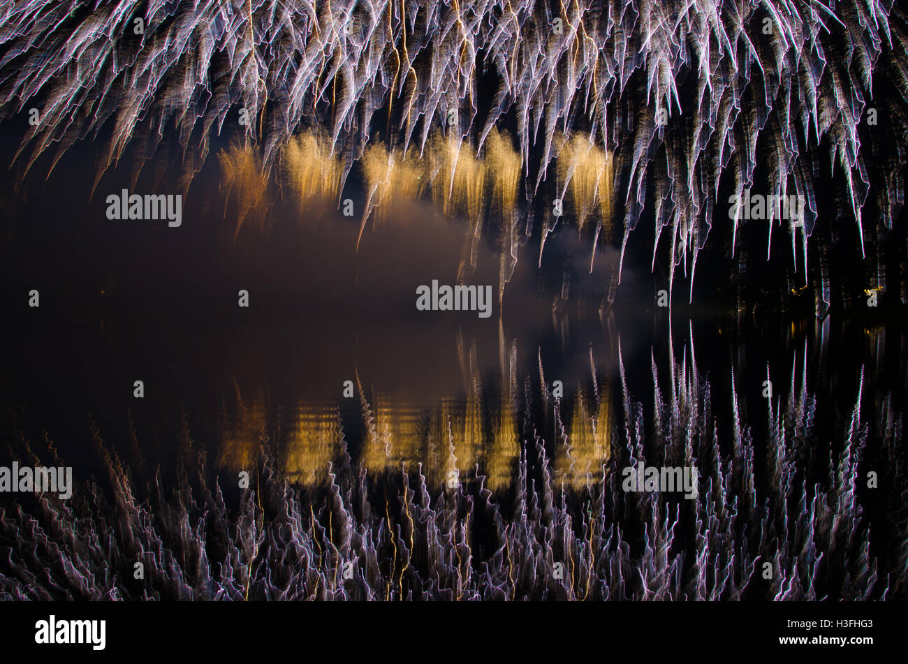 Fireworks reflecting on water at night Stock Photo