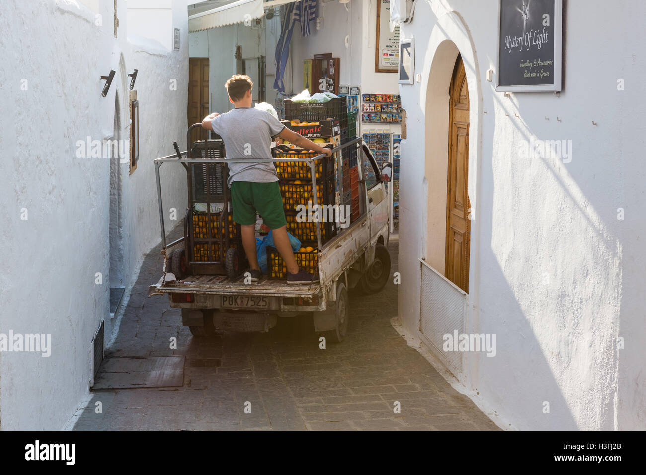 A delivery van negotiates the narrow streets of Lindos, Rhodes, Greece Stock Photo