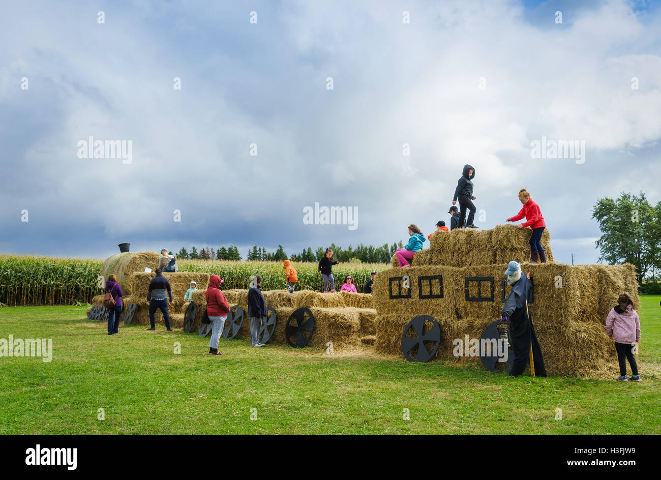 Adults and children playing on a straw choo choo train at a farm fair in rural Canada. Stock Photo