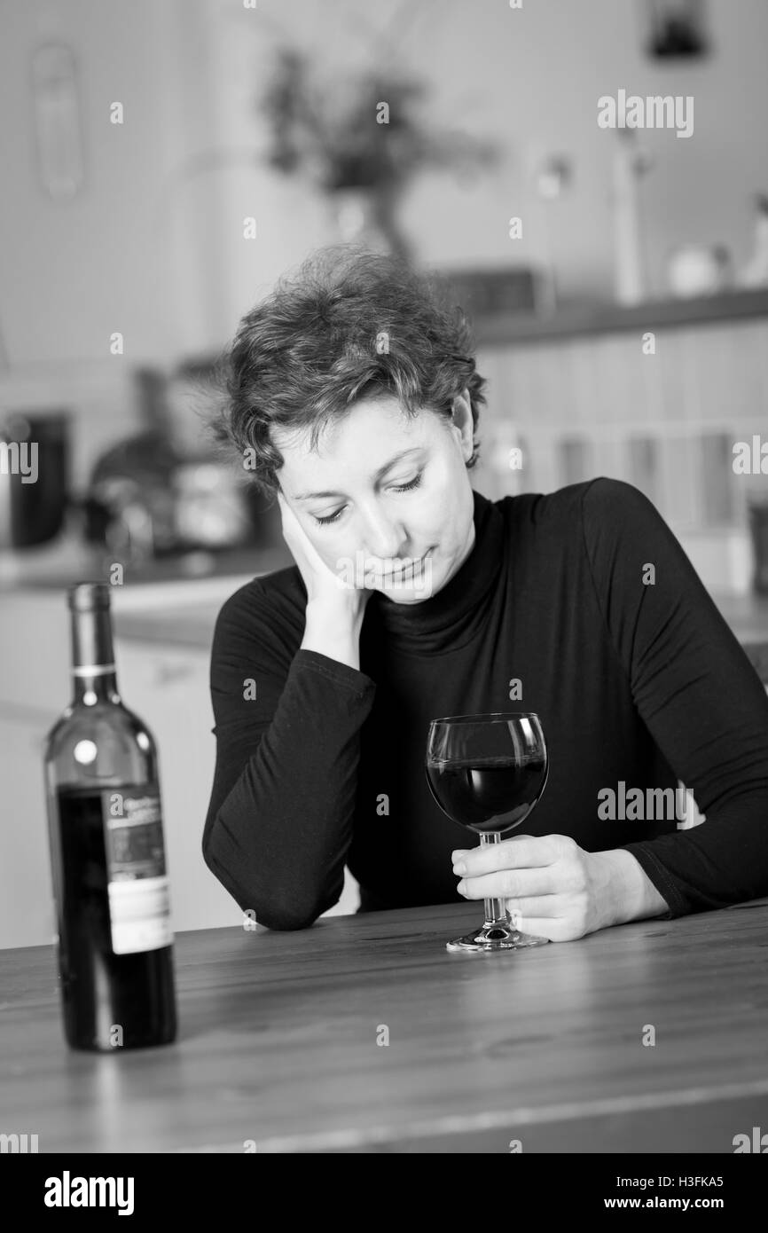 Black and white photograph of a Young woman in grief drinking red wine Stock Photo