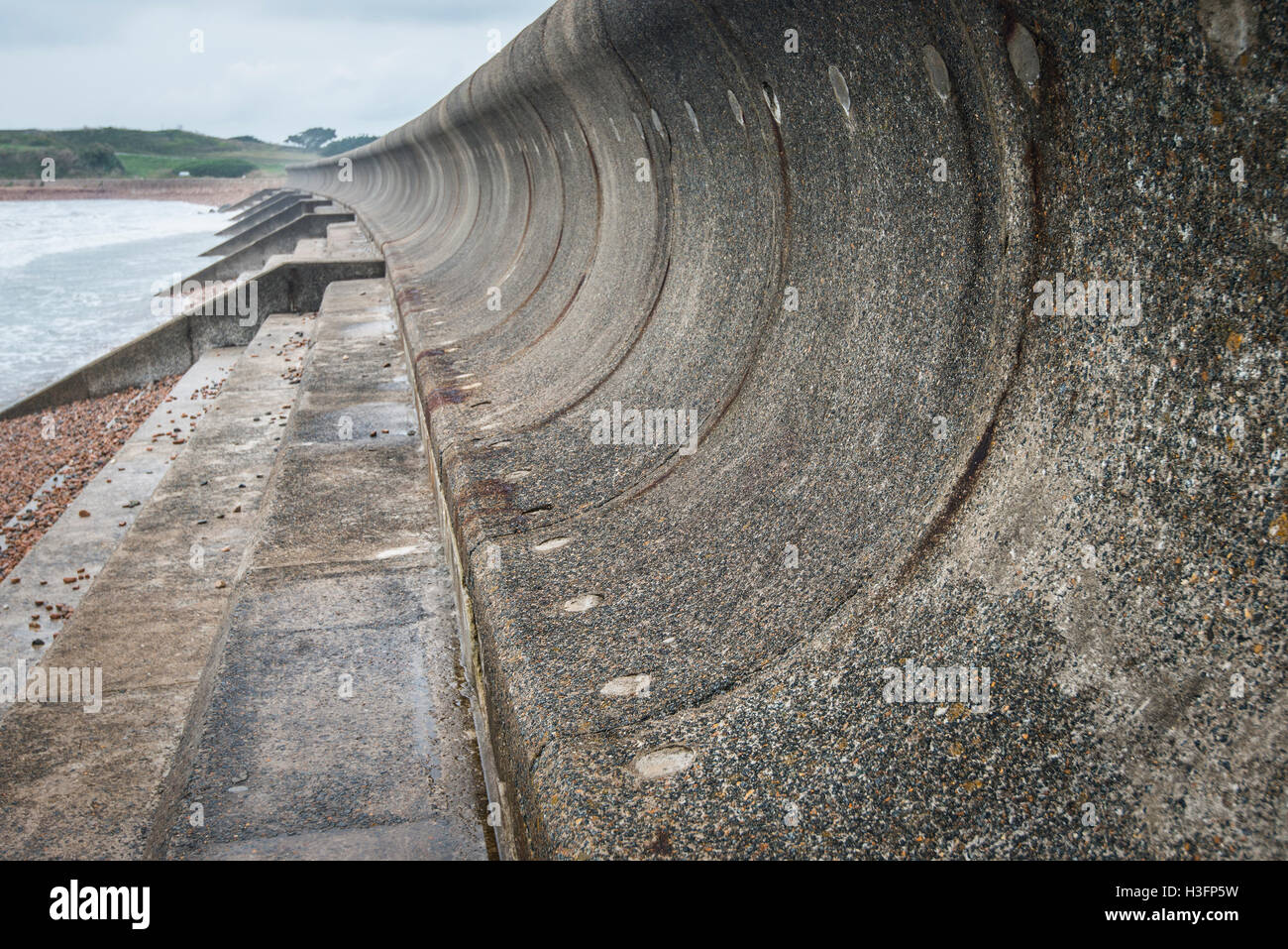 Curved sea wall which will reflect the energy of the waves back to the sea. Stock Photo