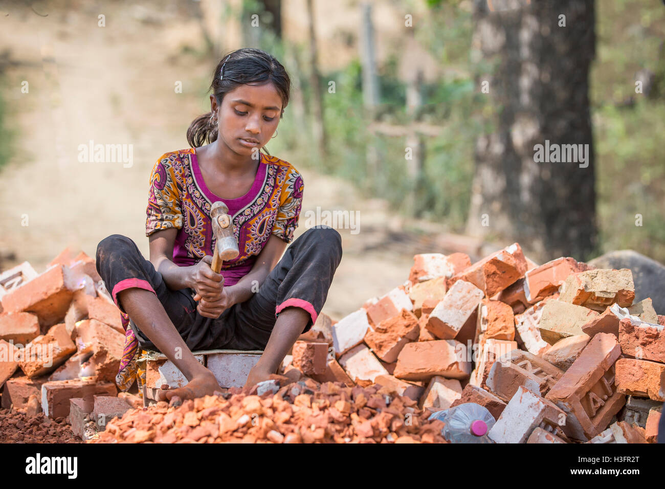 Chittagong, Bangladesh, February 25th, 2016: young girl is destroying old bricks with a hammer Stock Photo