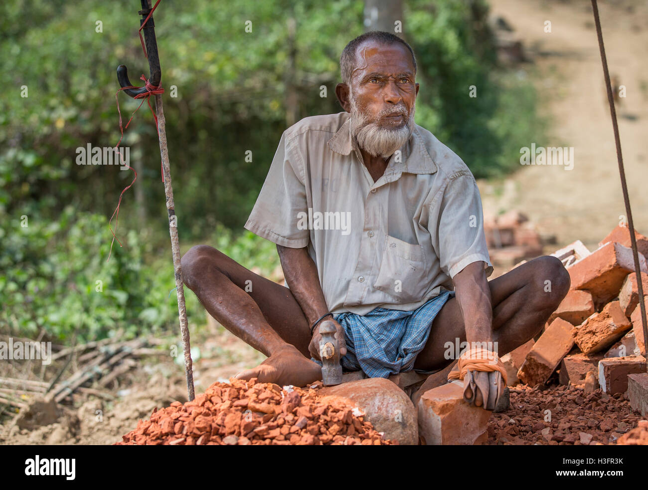 Chittagong, Bangladesh, February 25th, 2016: Old man destroying brick with a hammer Stock Photo