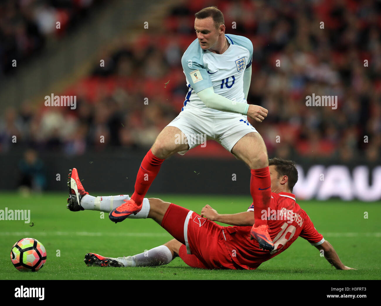 England's Wayne Rooney jumps over a challenge from Malta's Bjorn Kristensen during the 2018 FIFA World Cup Qualifying match at Wembley Stadium, London. Stock Photo