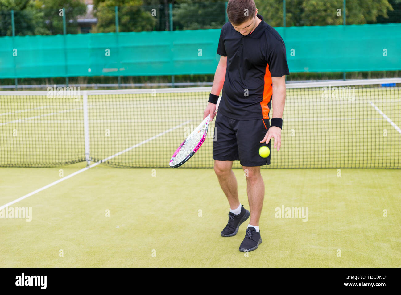 Male tennis player wearing a sportswear and holding a racket throws the