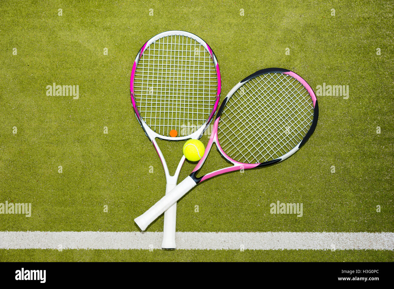 Two new pink tennis rackets with a tennis ball on a green grass court ...