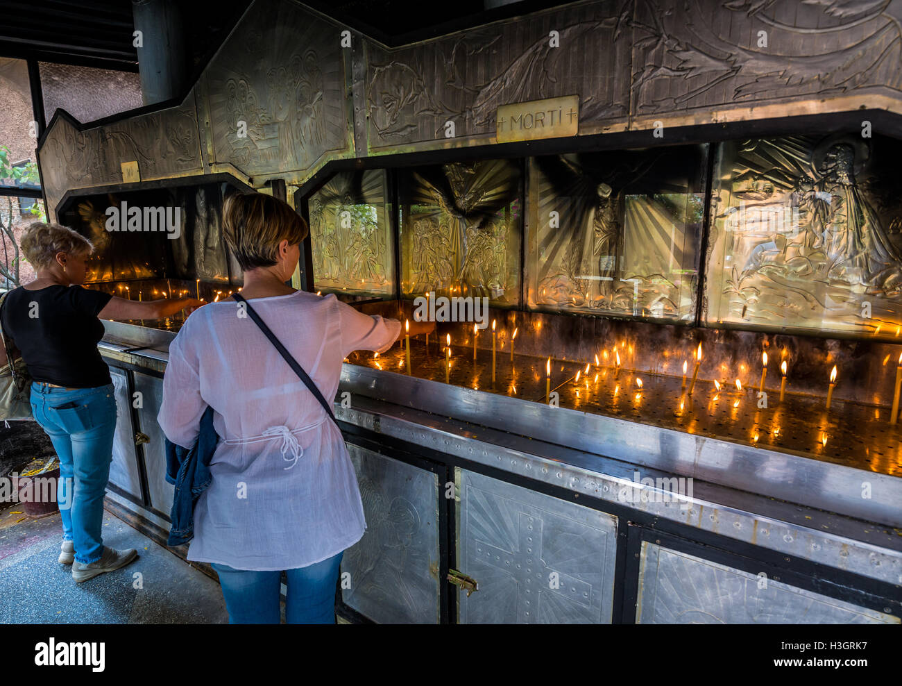 Woman lighting votive candle in Orthodox church of the Dormition of the