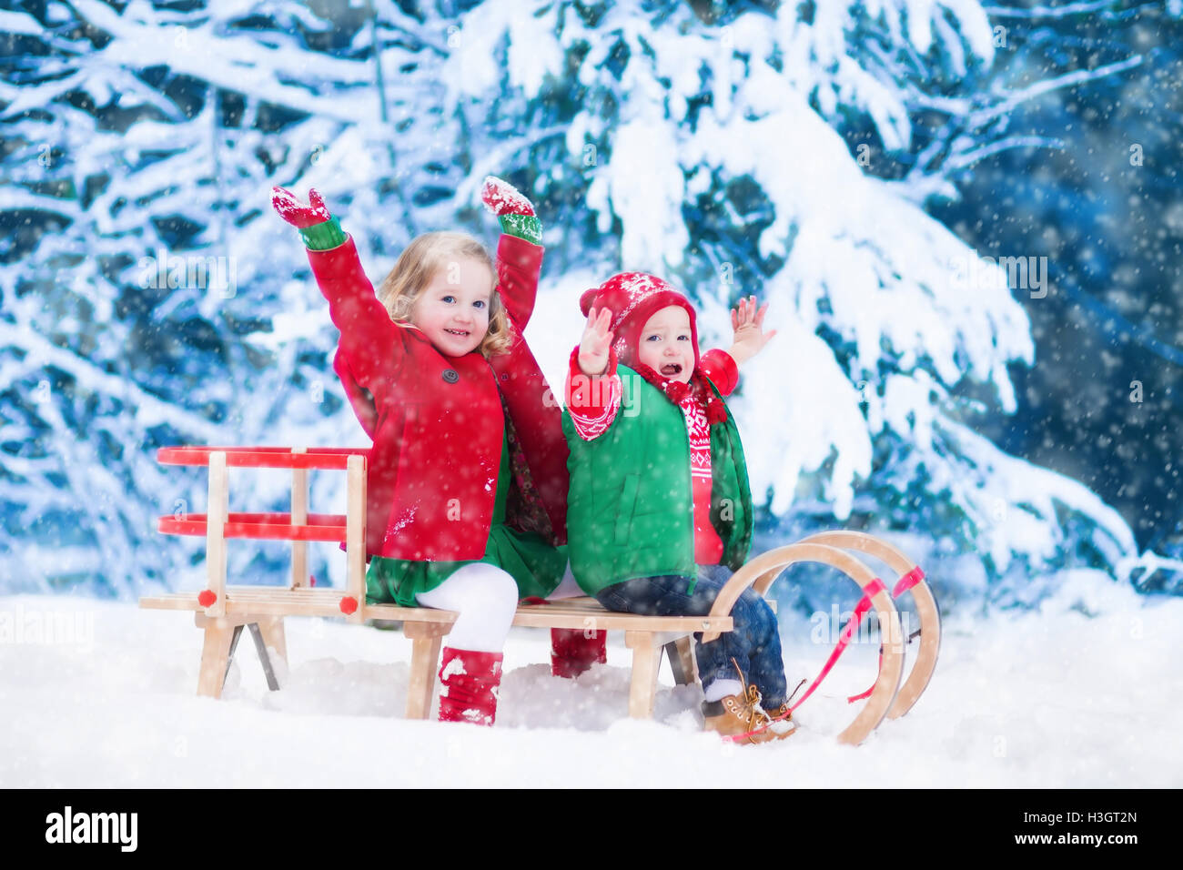 Infant Sleigh Riding Little girl and boy enjoy a sleigh ride. Child sledding. Toddler kid ...