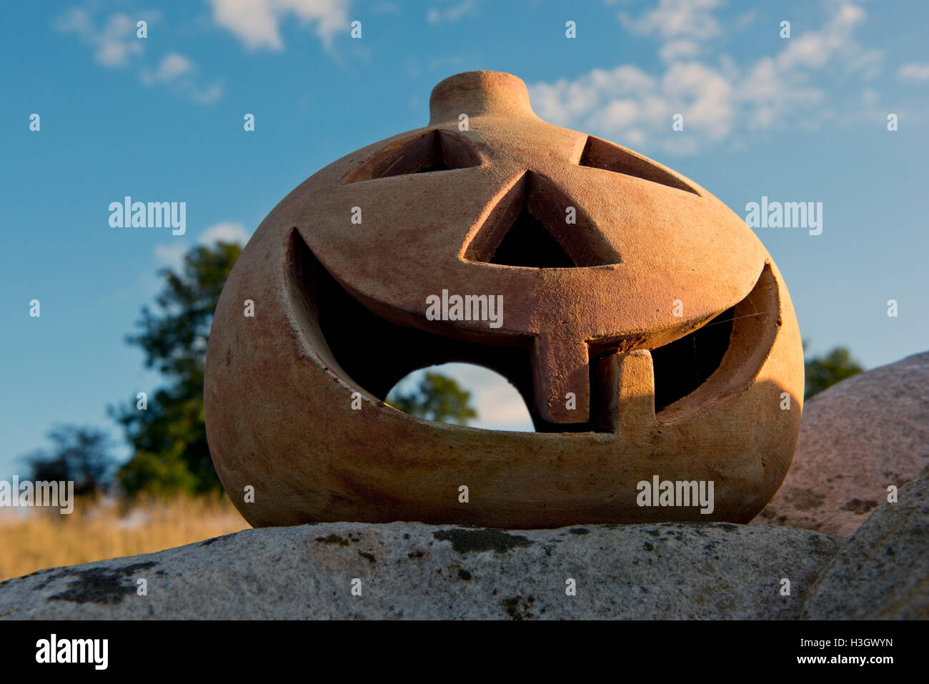 A terracotta pumpkin with eyes, nose and mouth and two teeth, ready for Halloween Stock Photo