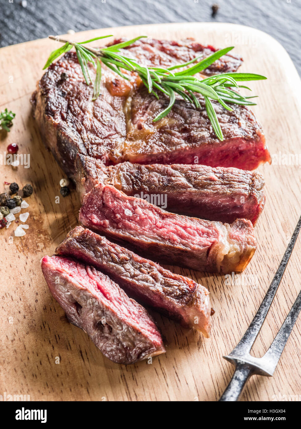 Medium Ribeye steak with spices on the wooden tray. Stock Photo