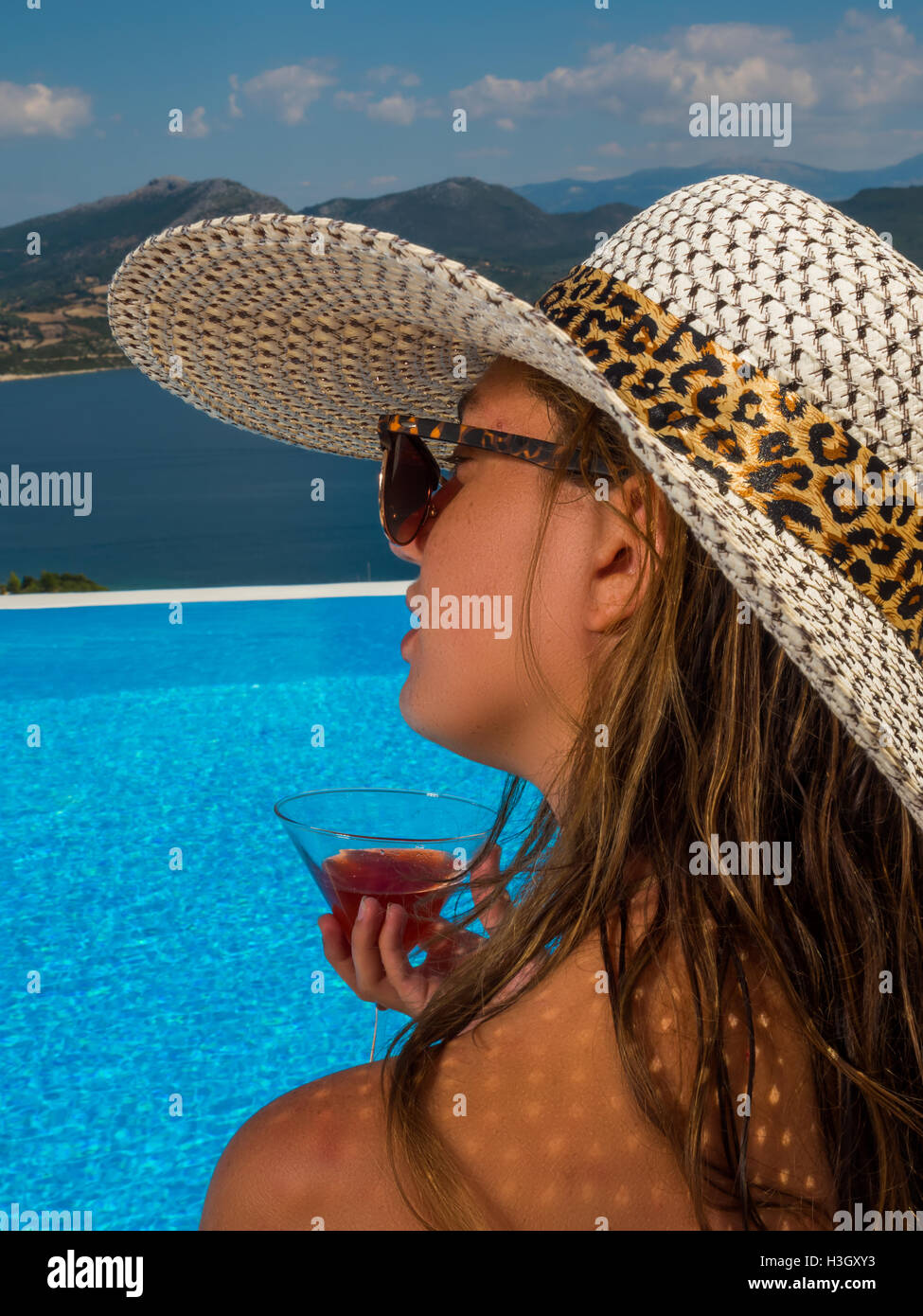 Beautiful woman with a hat is relaxing in an infinity pool with a ...