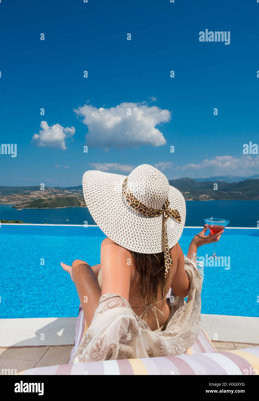 Woman relaxing at the infinity swimming pool looking at view Stock