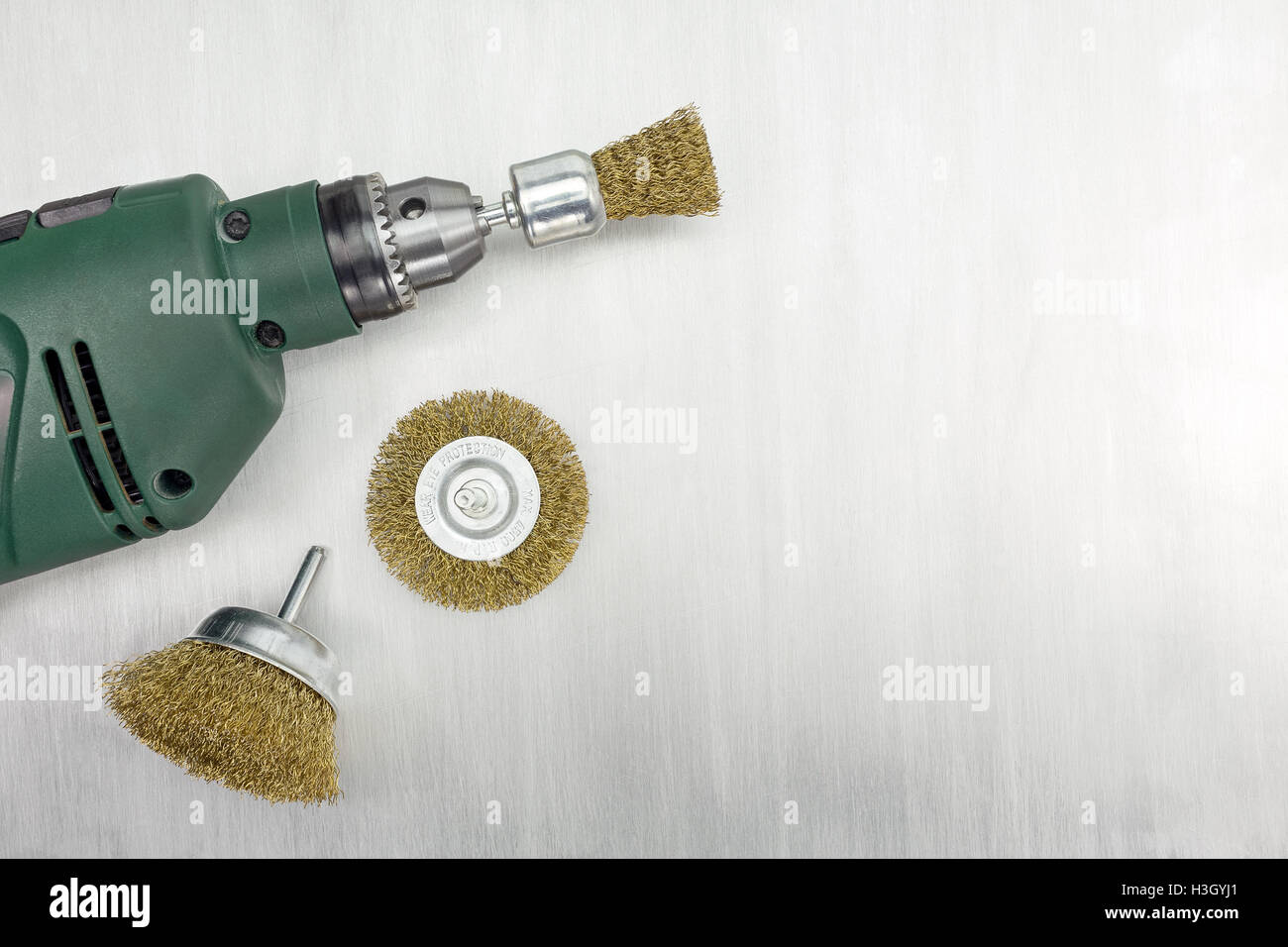 Electric drill and rotating metal brushes on scratched background Stock Photo