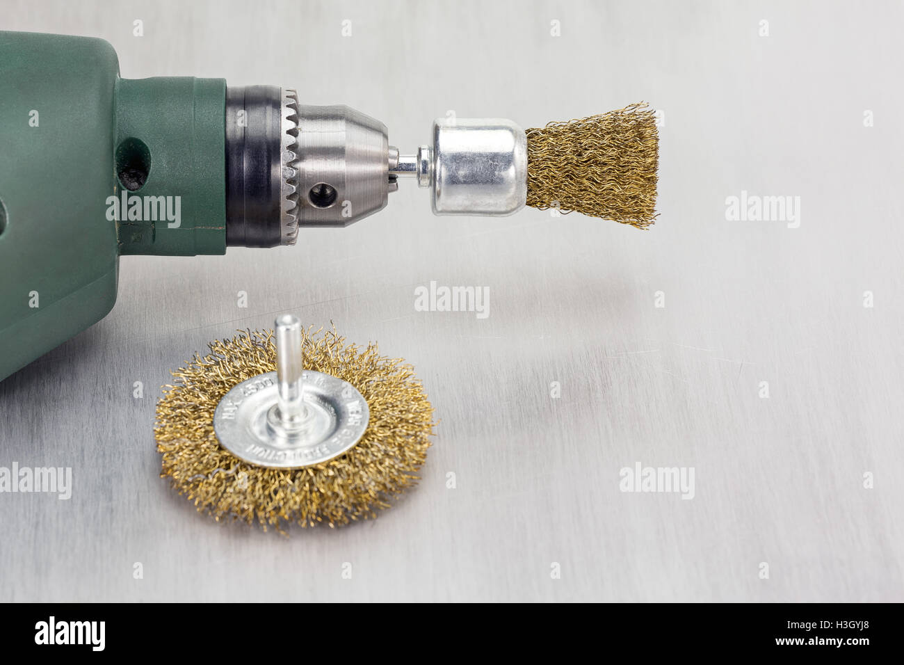 Electric drill with rotating metal brushes on scratched background Stock Photo